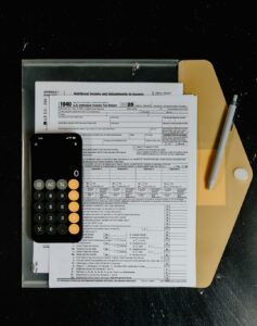 A couple reviewing tax documents and a Form 1040 at a kitchen table with a calculator and folders.