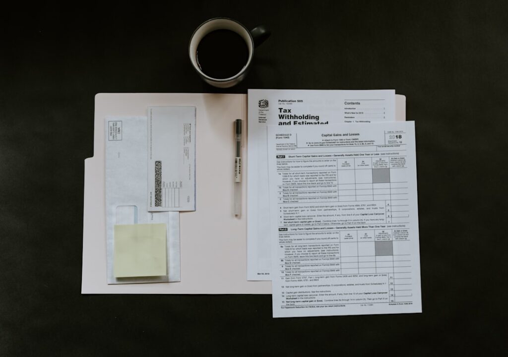 A person sorting tax forms, receipts, and identification documents at a kitchen table with a calculator.