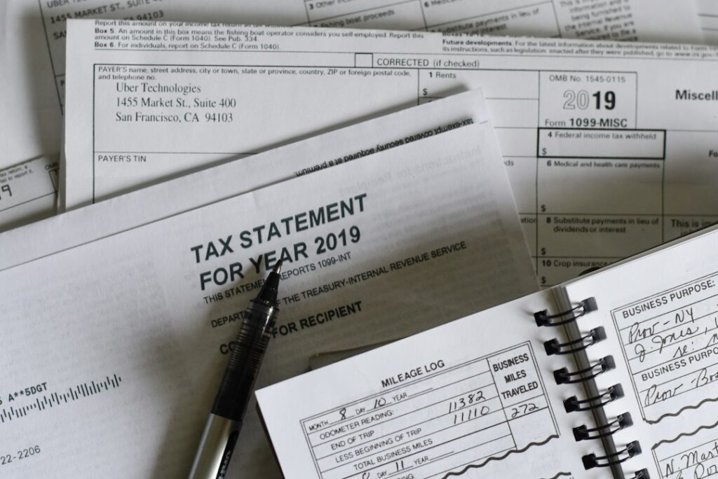A freelancer reviews receipts, payment records, and a mileage log at a home desk.