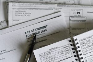 A freelancer reviews receipts, payment records, and a mileage log at a home desk.
