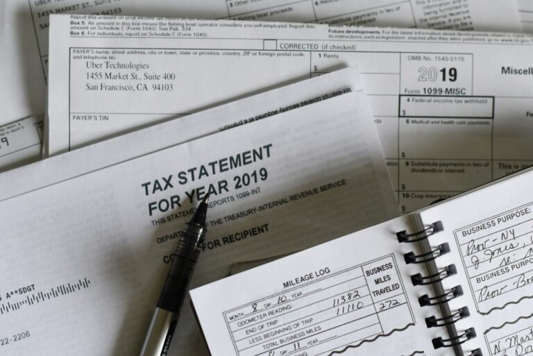 A freelancer reviews receipts, payment records, and a mileage log at a home desk.