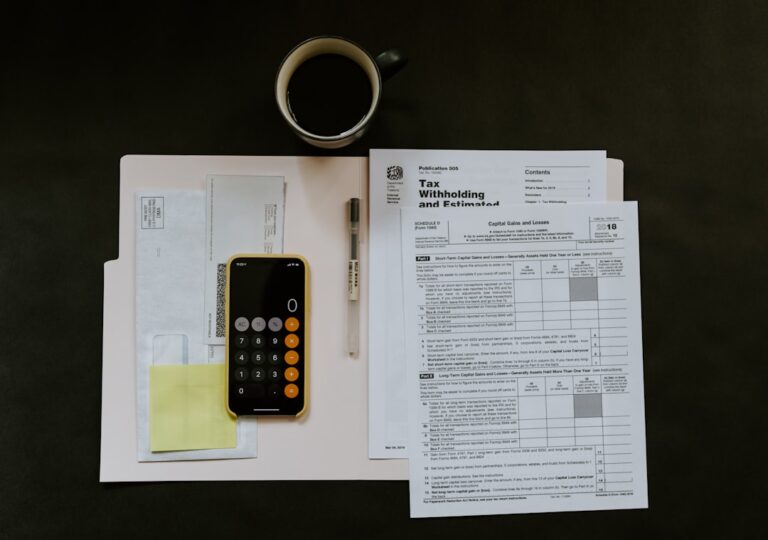 A person organizing tax documents and receipts at a dining table with a calculator and coffee mug nearby.
